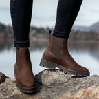 Mujer de pie junto al lago usando botines Kalver Sierra café en otoño
